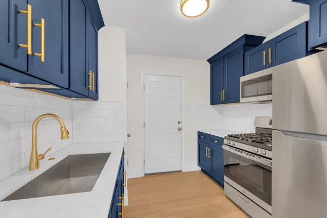 a kitchen with granite countertop a sink cabinets and stainless steel appliances