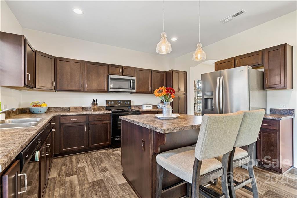 12510 Gotland Road Midland, NC 28107 - Photo 4 of 30 a kitchen with stainless steel appliances granite countertop a stove top oven a sink dishwasher a dining table and chairs with wooden floor