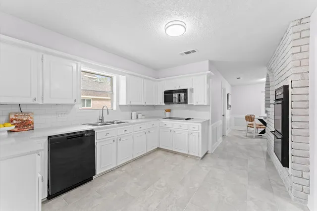 a hall with stainless steel appliances white cabinets and a sink