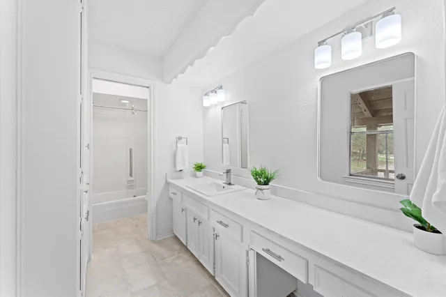 a spacious en suite bathroom with a granite countertop sink and a mirror