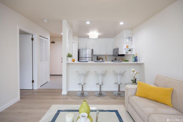 a living room with stainless steel appliances kitchen island granite countertop furniture and a couch