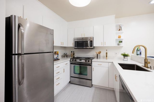 a kitchen with white cabinets and stainless steel appliances