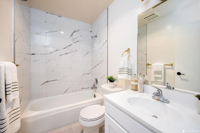 a bathroom with a bathtub shower sink mirror vanity and toilet