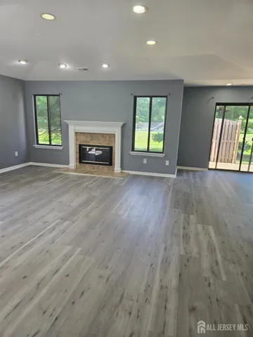 an empty room with wooden floor fireplace and windows
