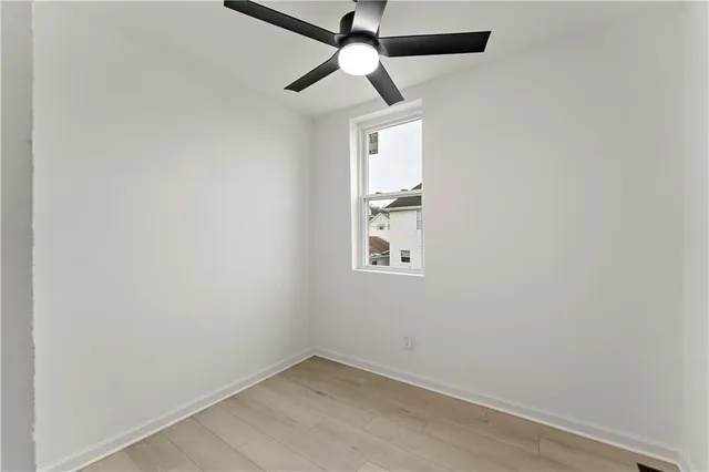 an empty room with a window and a fan