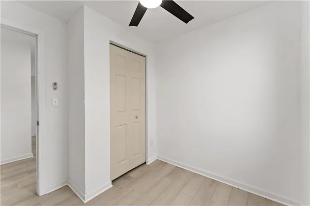 an empty room with ceiling fan and window