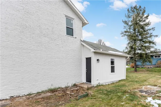 a view of a white house with a yard and large tree