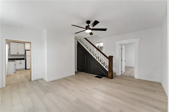 a view of an empty room with wooden floor and a ceiling fan