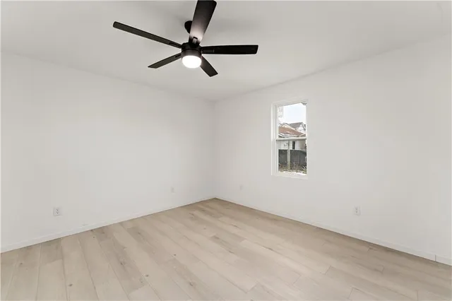 an empty room with a ceiling fan and window