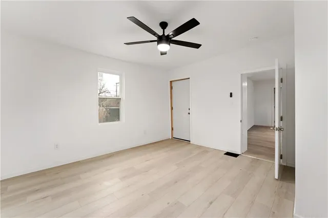 an empty room to ceiling fan and window