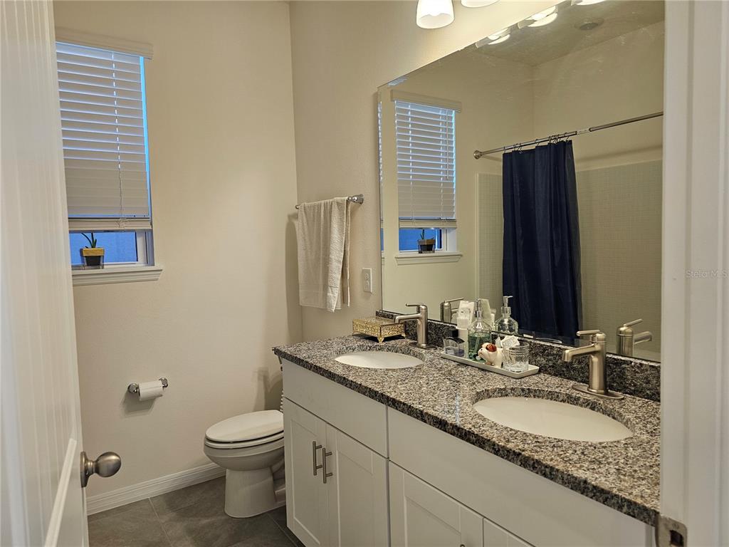 2045 Rankin Street Kissimmee, FL 34744 - Photo 16 of 38 a bathroom with a granite countertop toilet sink and mirror