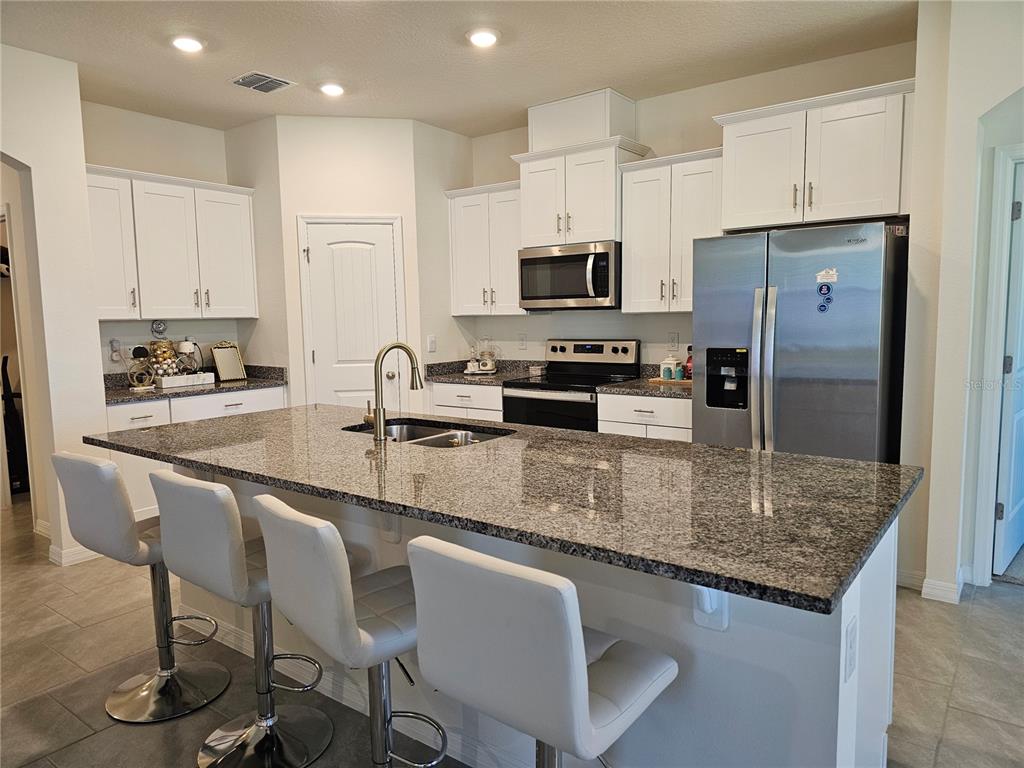 2045 Rankin Street Kissimmee, FL 34744 - Photo 7 of 38 a kitchen with stainless steel appliances granite countertop a sink a stove a table and chairs