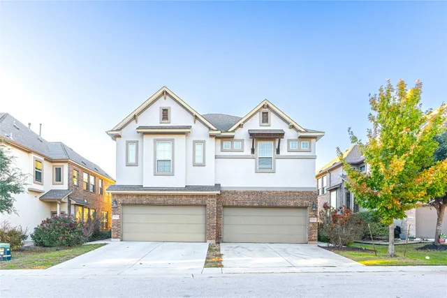 a view of a white house with a large windows and a yard with plants