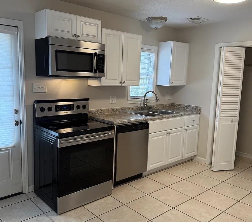 928 Poplar Leaf Road Collierville, TN 38017 - Photo 3 of 8 Kitchen with stainless steel appliances, white cabinets, dark countertops, and light tile patterned floors