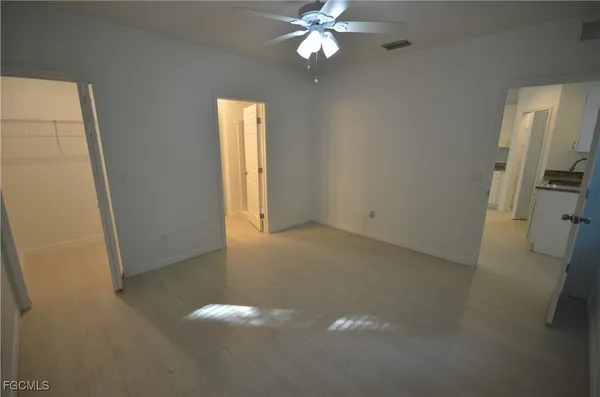 an empty room with a fan & a window