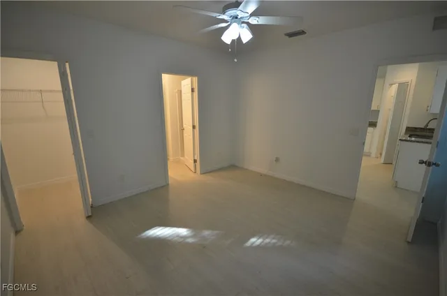 an empty room with a fan & a window