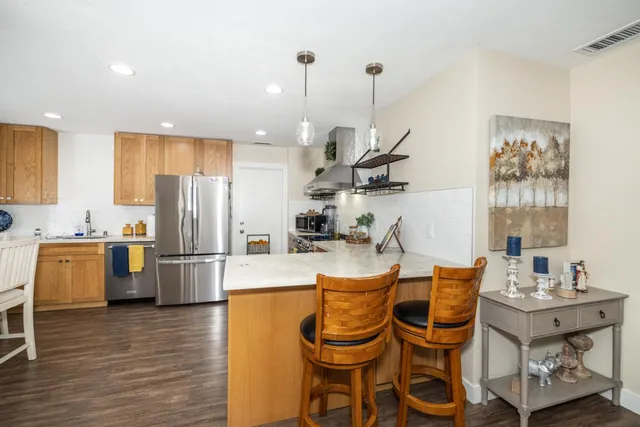 a kitchen with stainless steel appliances kitchen island granite countertop a table chairs and a refrigerator