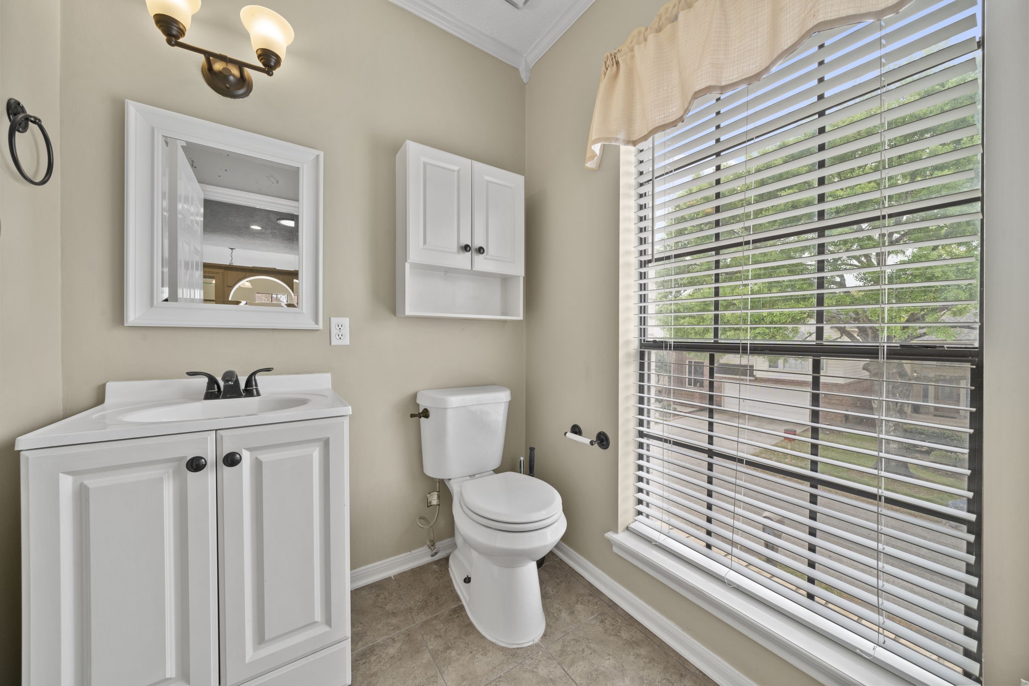 169 April Cove Montgomery, TX 77356 - Photo 17 of 39 Charming powder room featuring a clean, neutral design, framed mirror, and stylish lighting. A large window fills the space with natural light, creating a bright and inviting atmosphere for guests.