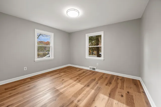 a view of an empty room with window and wooden floor