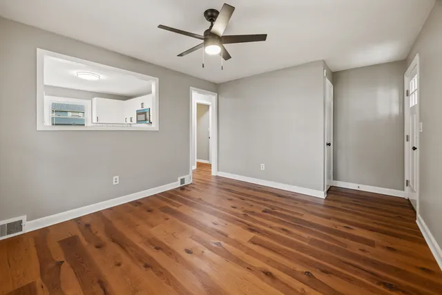a view of empty room with wooden floor and fan