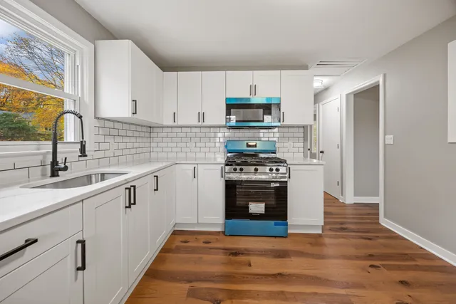 a kitchen with stainless steel appliances a sink cabinets and a window