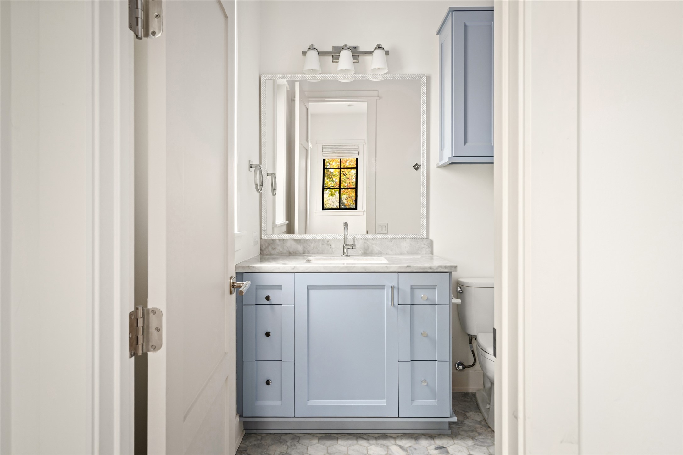 1136 Woodland Street Houston, TX 77009 - Photo 36 of 50 Charming secondary bath featuring a custom vanity with marble countertop, hex tile flooring, and polished fixtures beneath a framed mirror.