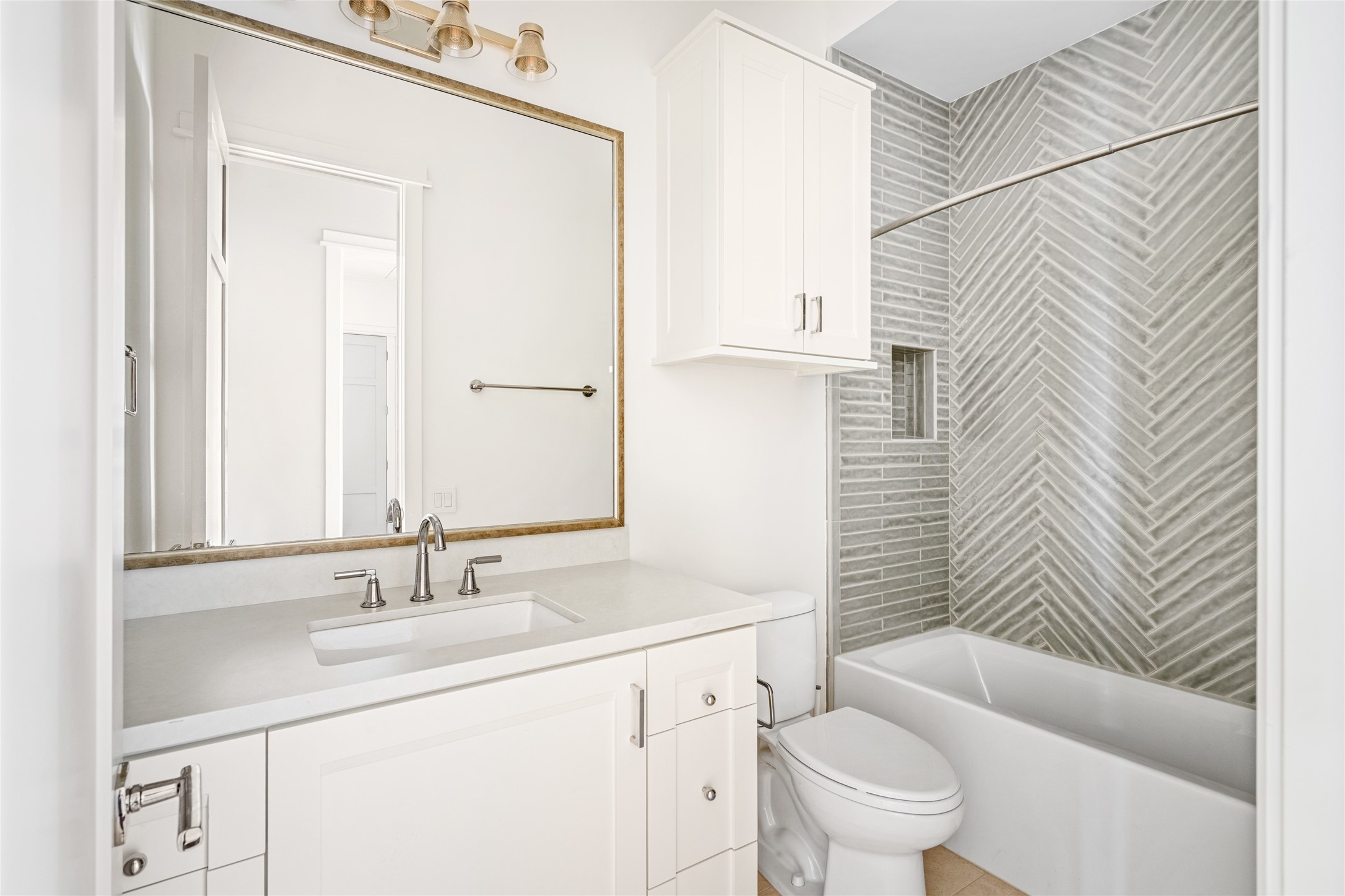 1136 Woodland Street Houston, TX 77009 - Photo 40 of 50 Well-appointed full bath with custom cabinetry, quartz countertop, and a tub/shower combination accented by herringbone tile surround.