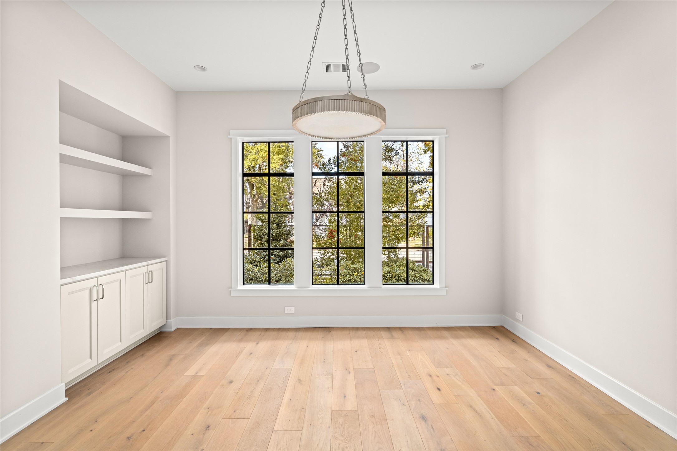 1136 Woodland Street Houston, TX 77009 - Photo 4 of 50 Private home office with high ceilings, built-in storage, and leafy street views—an ideal work-from-home retreat filled with natural light.