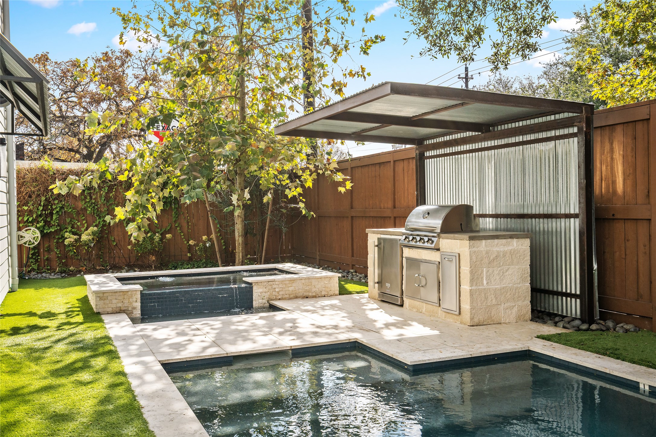 1136 Woodland Street Houston, TX 77009 - Photo 46 of 50 Resort-style backyard featuring a heated saltwater pool and spa, covered outdoor kitchen, fire pit, and multiple lounging areas surrounded by mature landscaping.