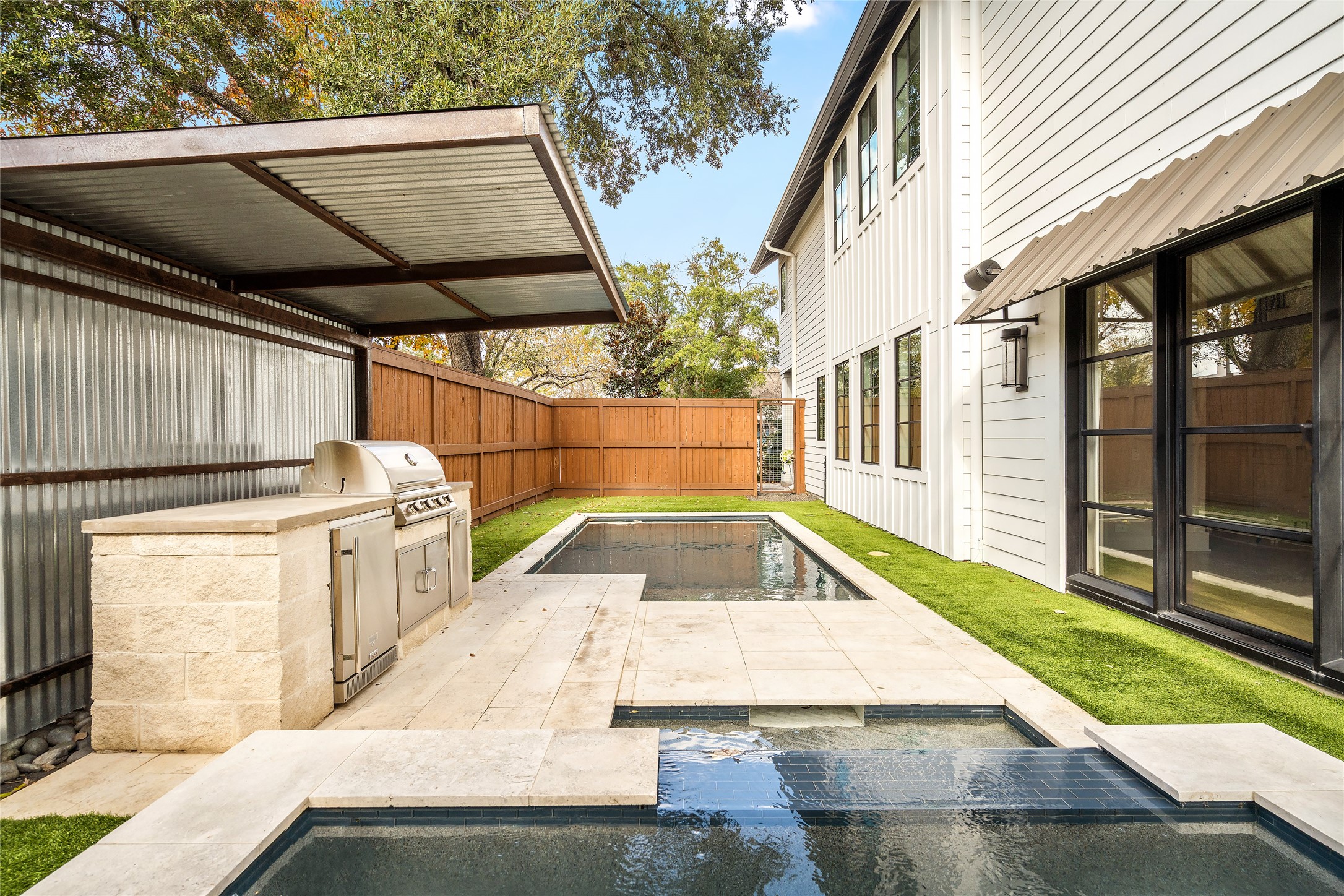 1136 Woodland Street Houston, TX 77009 - Photo 48 of 50 Custom outdoor kitchen with built-in grill, storage, and prep space beneath a contemporary metal canopy.