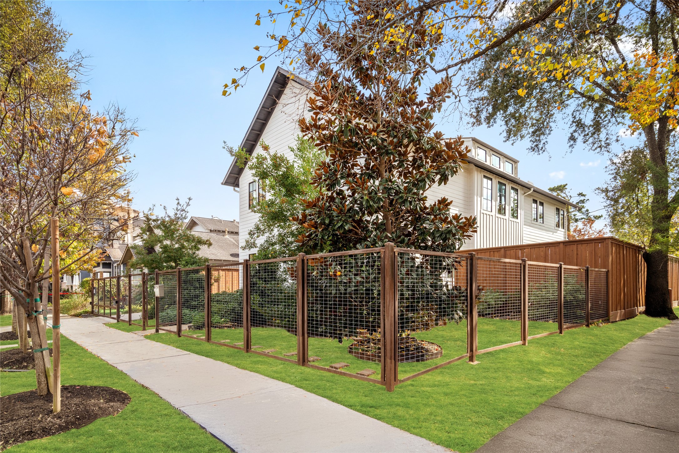 1136 Woodland Street Houston, TX 77009 - Photo 50 of 50 A striking corner-lot presence with crisp modern siding, mature trees, and a custom steel-and-wood fence that defines both privacy and curb appeal.