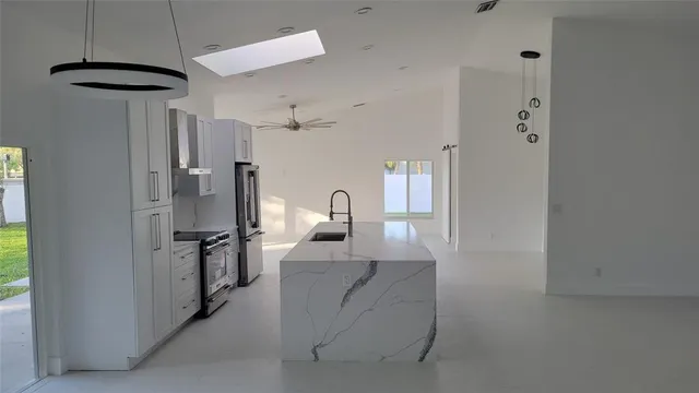 a hall way with stainless steel appliances a refrigerator and a window