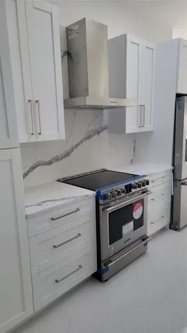 a kitchen with granite countertop white cabinets and white stove