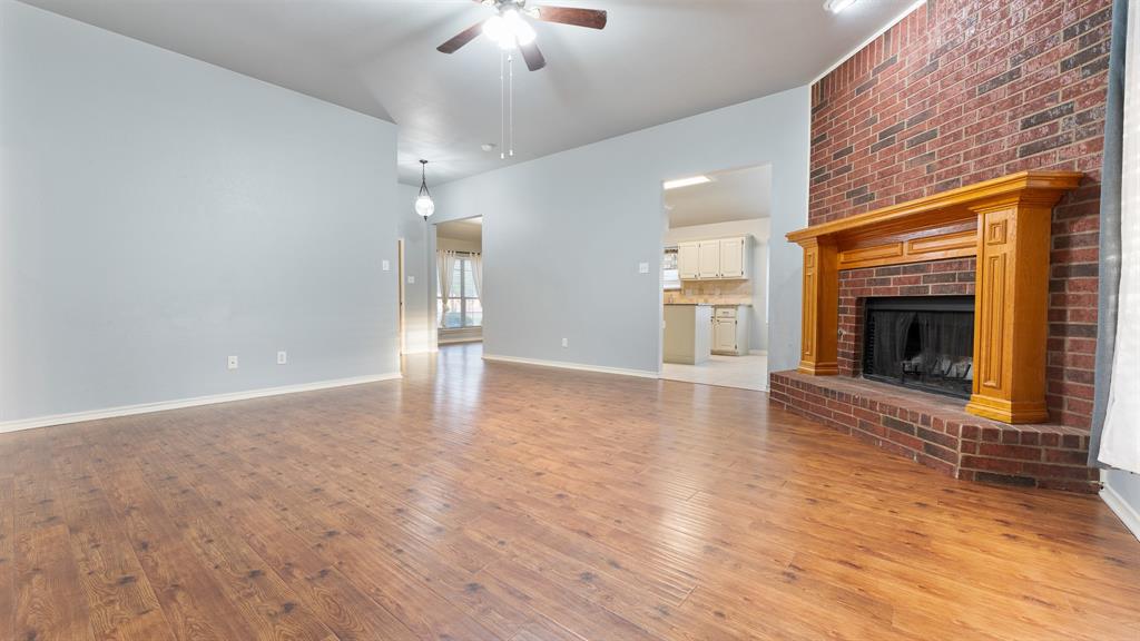 525 Mustang Ridge Drive Murphy, TX 75094 - Photo 10 of 26 an empty room with wooden floor fireplace cabinet and windows