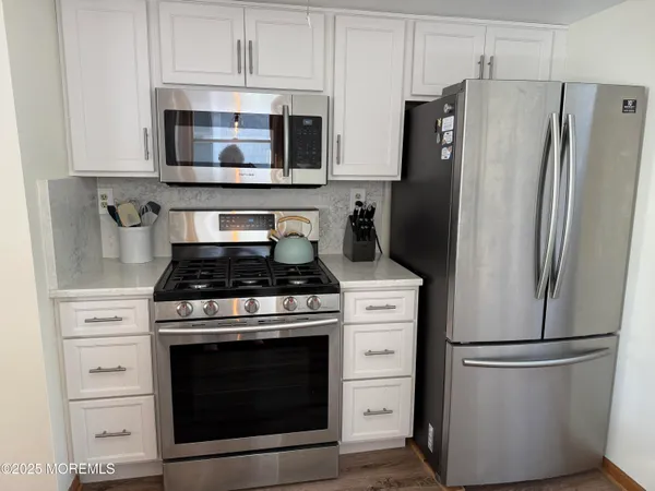 a kitchen with stainless steel appliances a refrigerator stove and white cabinets