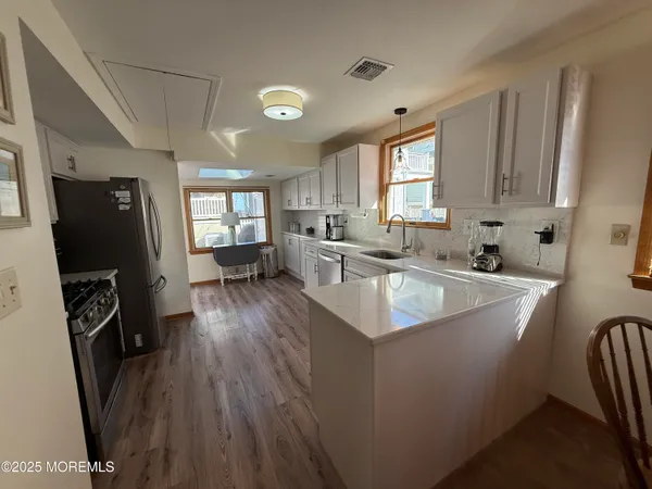 a large kitchen with stainless steel appliances a stove a sink dishwasher a refrigerator a oven and a dining table with wooden floor