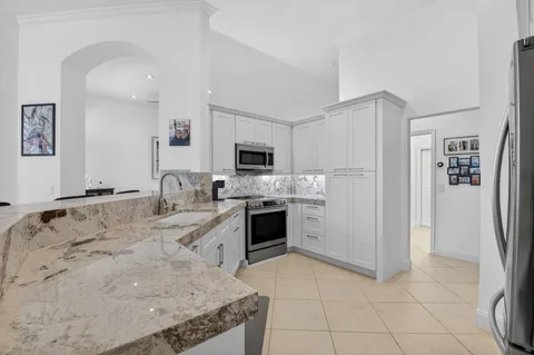 a kitchen with granite countertop white cabinets and stainless steel appliances
