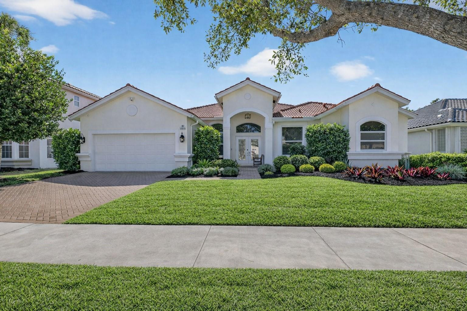 10078 Lexington Estates Boulevard Boca Raton, FL 33428 - Photo 3 of 49 a front view of a house with a garden and trees