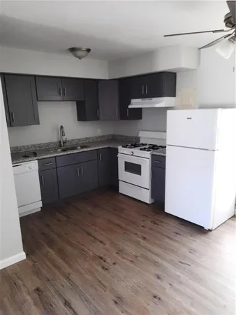 a kitchen with granite countertop wooden floors and white stainless steel appliances