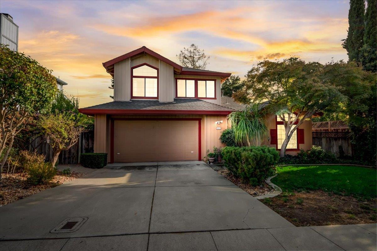 a front view of a house with a garden and trees
