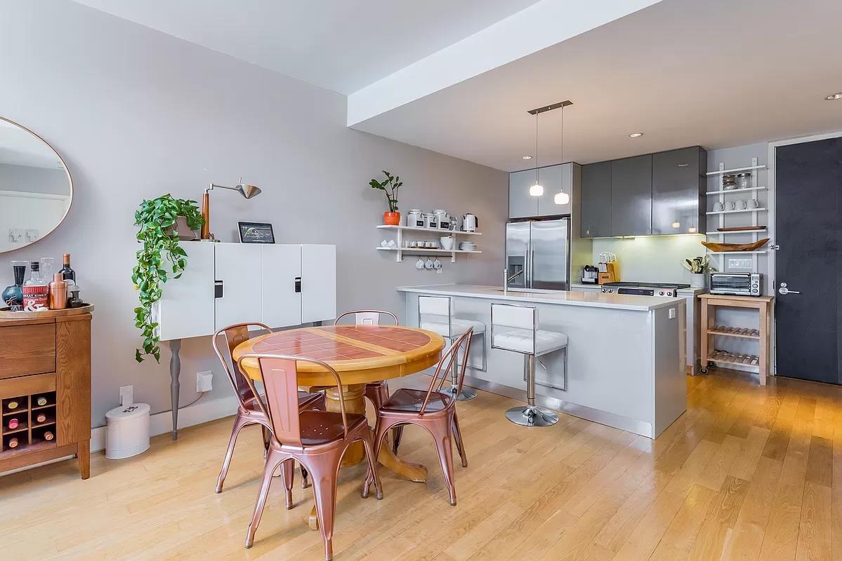 2-26 50th Avenue, Unit 11B Queens, NY 11101 - Photo 2 of 12 a kitchen with stainless steel appliances kitchen island granite countertop a dining table chairs and a refrigerator