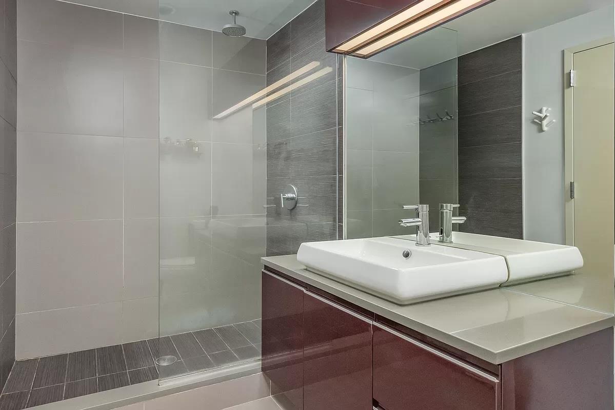 2-26 50th Avenue, Unit 11B Queens, NY 11101 - Photo 5 of 12 a bathroom with a sink a mirror and a shower