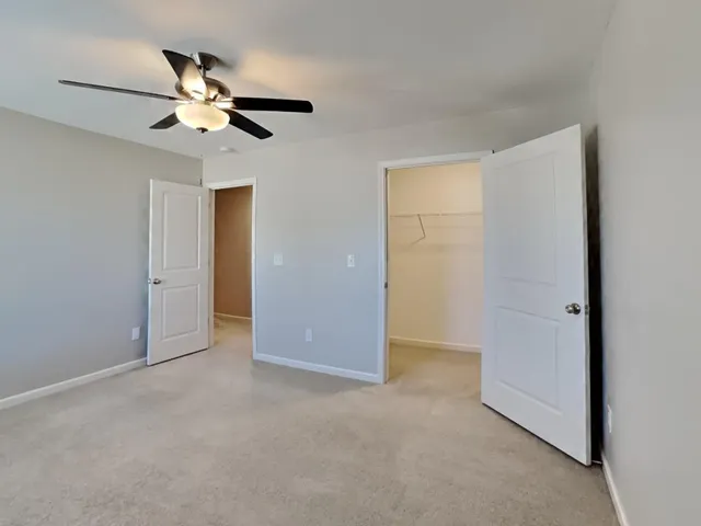 a view of an empty room with a chandelier fan