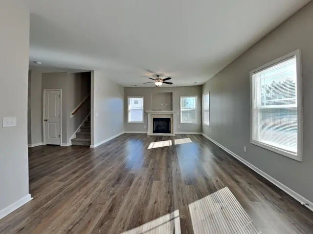 an empty room with wooden floor fireplace and windows
