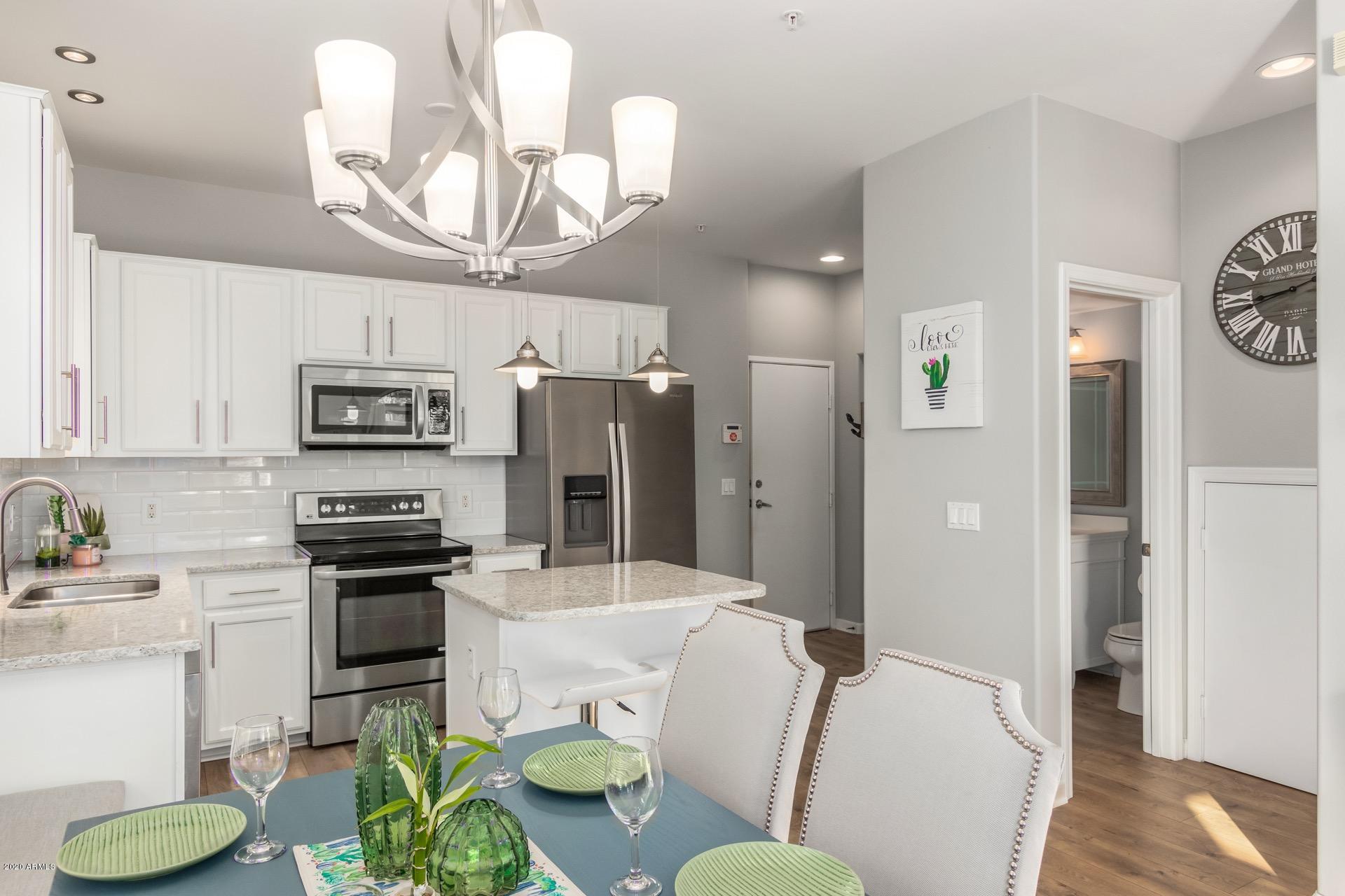 280 South Evergreen Road, Unit 1245 Tempe, AZ 85288 - Photo 8 of 28 a kitchen with stainless steel appliances granite countertop a refrigerator a stove a sink dishwasher a dining table and chairs with wooden floor