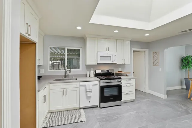 a kitchen with granite countertop white cabinets and white appliances