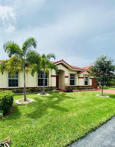 a front view of a house with a yard and trees