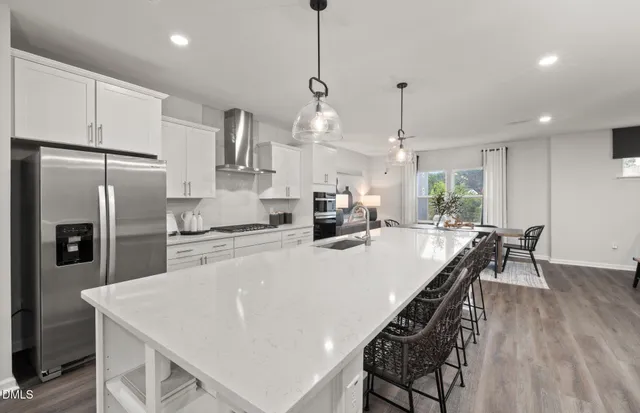 a kitchen with stainless steel appliances a dining table chairs stove and refrigerator
