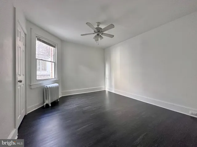 an empty room with wooden floor chandelier fan and windows