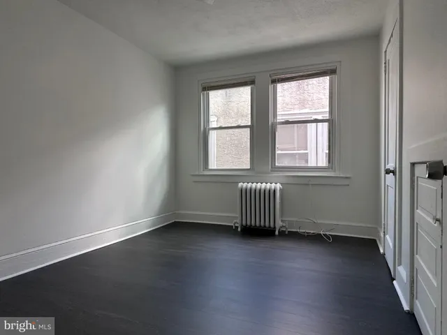 a view of an empty room with closet and wooden floor